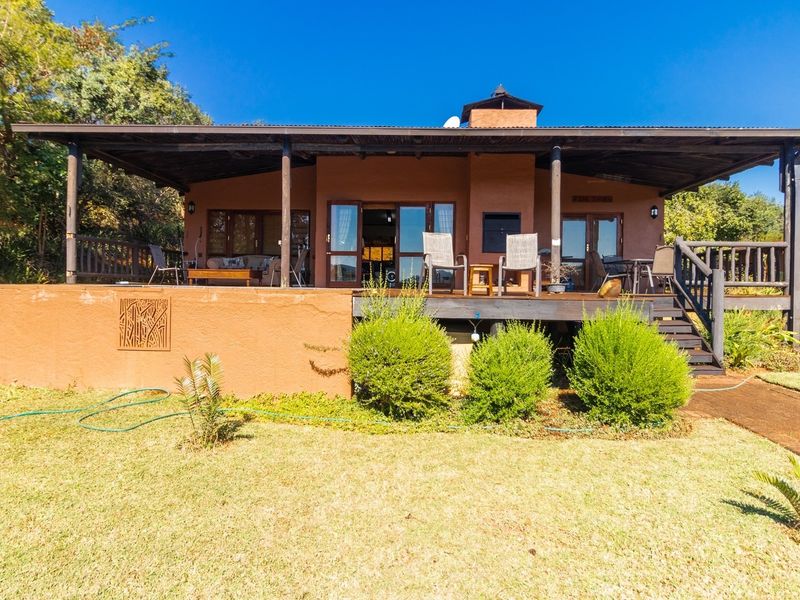 Rear view of the house featuring a spacious covered timber deck, built-in fireplace, and direct access to the garden through sliding glass doors.