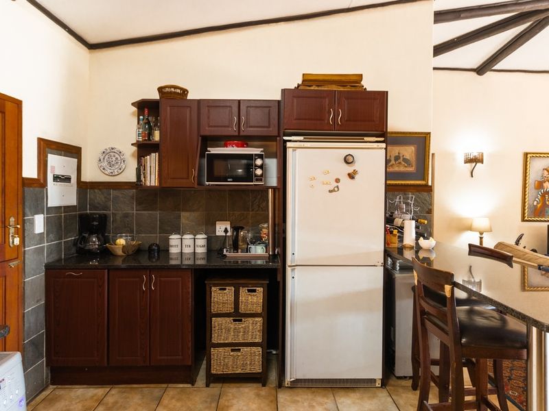 Open-plan kitchen area featuring dark wood cabinetry, granite countertops, a breakfast bar, and exposed ceiling beams, seamlessly connecting to the living space.