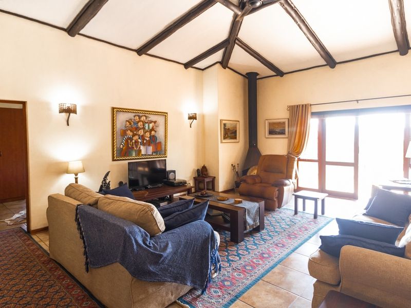Spacious living room featuring exposed timber ceiling beams, a freestanding fireplace, and tiled flooring, with direct access to an outdoor area.
