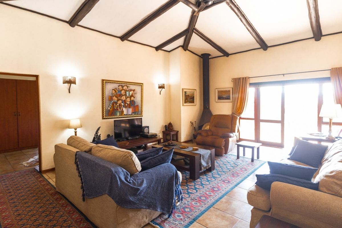 Spacious living room featuring exposed timber ceiling beams, a freestanding fireplace, and tiled flooring, with direct access to an outdoor area.