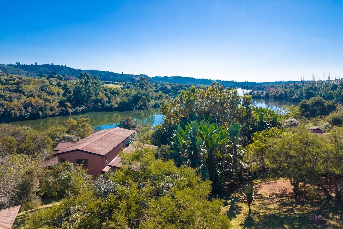 Aerial view of a residential property nestled in a lush, green landscape with direct access to a scenic river or lake.
