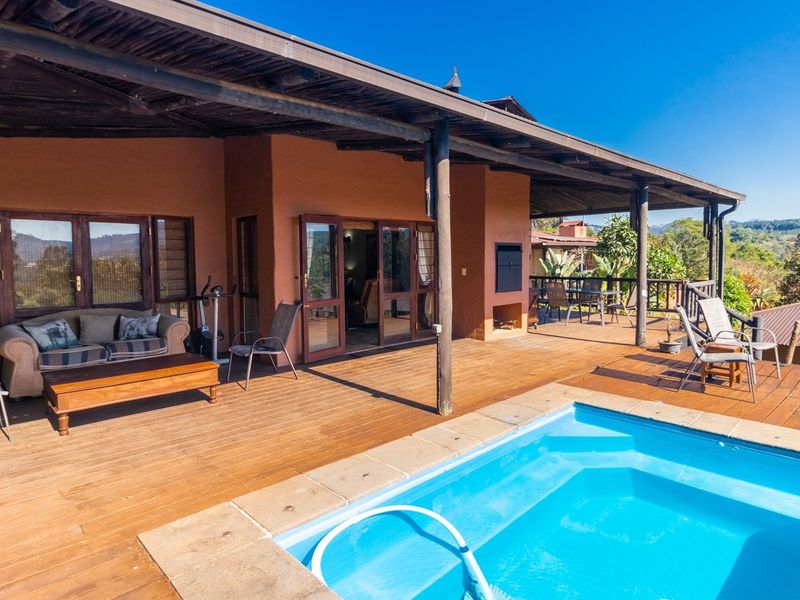Spacious covered timber deck featuring a built-in braai and an integrated swimming pool, offering an ideal outdoor entertainment area with scenic views.