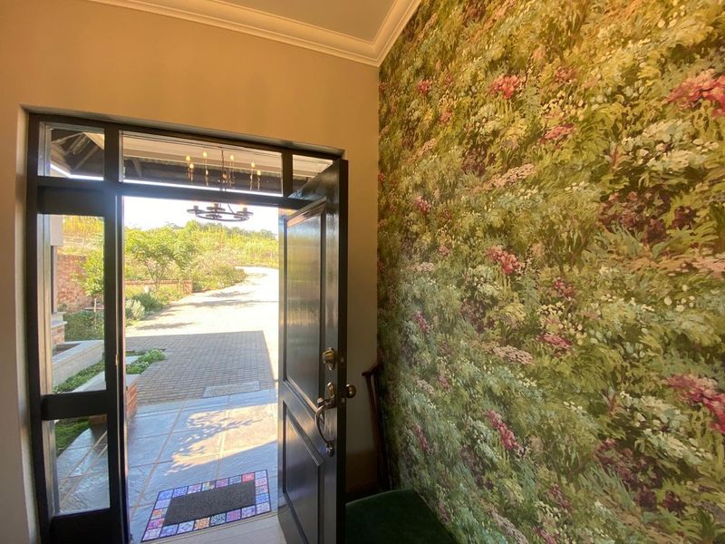 Welcoming entrance hall featuring decorative floral wallpaper, cove cornicing, and a solid timber door opening to the exterior driveway.