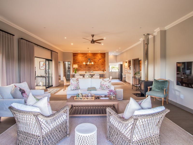 Spacious open-plan living area featuring an exposed brick wall, a modern freestanding fireplace, and seamless flow to the kitchen and outdoor access.