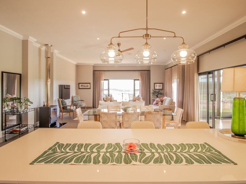 Spacious open-plan living and dining area featuring a modern kitchen island, sleek quartz countertops, and a cozy freestanding fireplace with large sliding glass doors.
