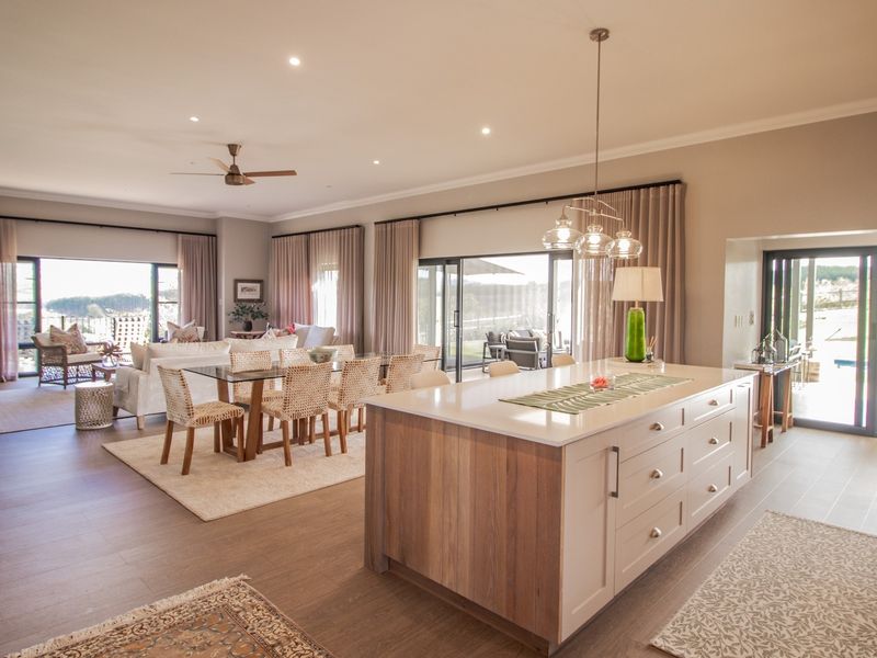 Spacious open-plan living area featuring a modern kitchen island, wood-burning fireplace, and large sliding glass doors leading to outdoor spaces.