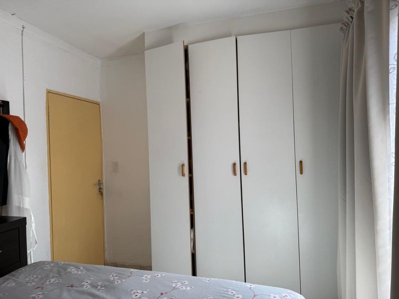 A bedroom featuring a white built-in wardrobe with multiple doors and a standard internal door.