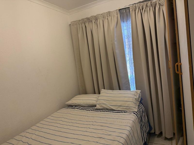 A compact bedroom featuring a built-in wardrobe and neutral wall finishes, providing a functional space for rest.