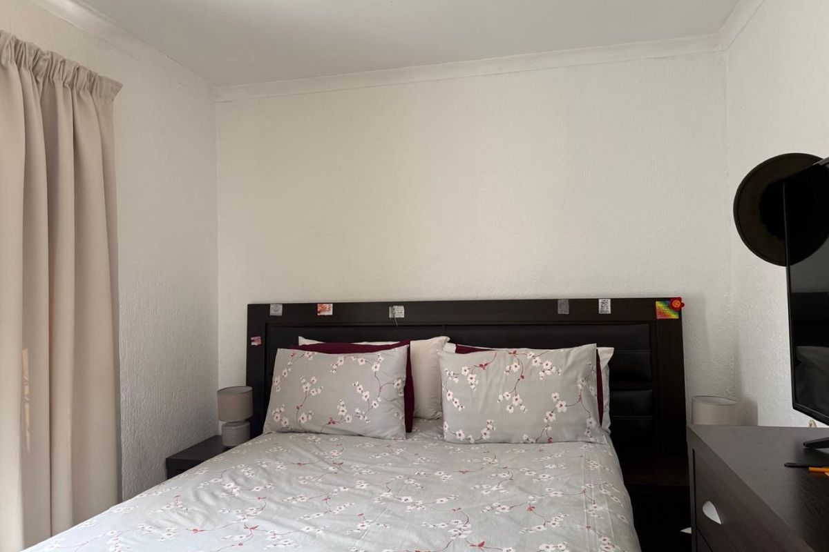 A standard bedroom featuring neutral wall finishes and a curtain rail, providing a functional and well-maintained sleeping space.