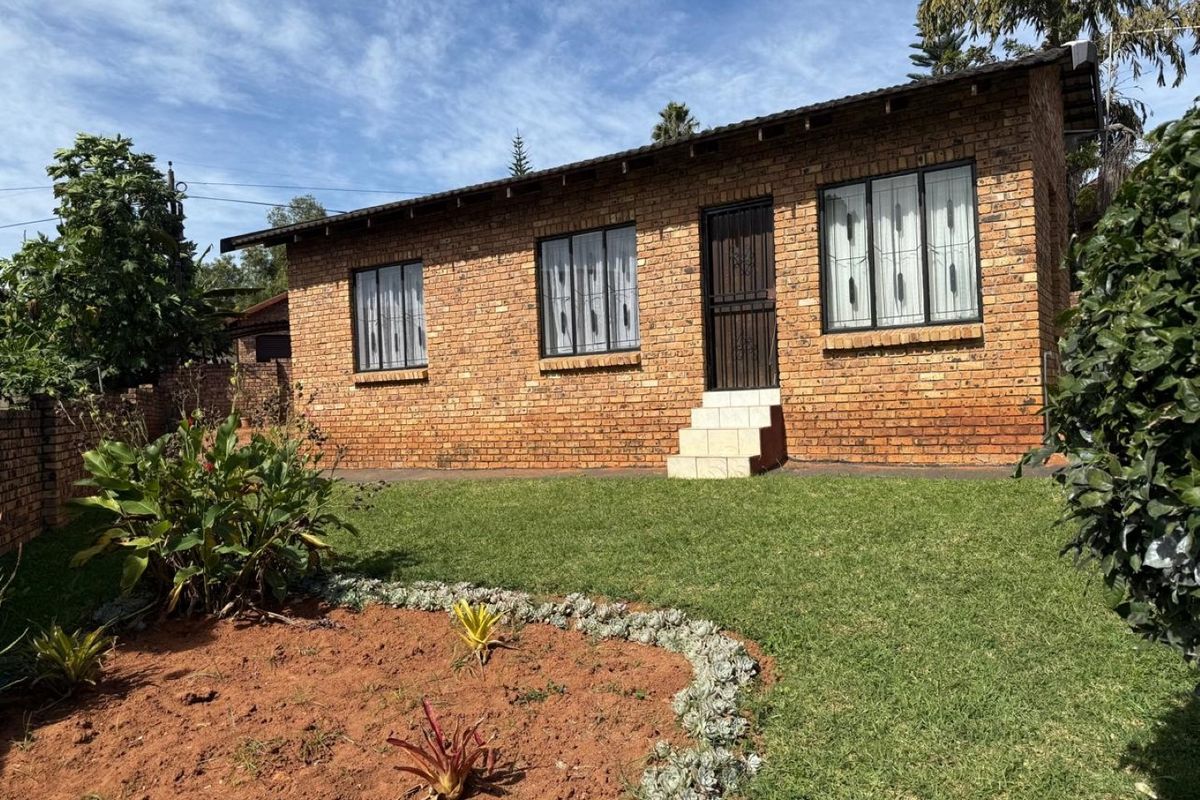A well-maintained face brick exterior featuring a tiled roof, secure window bars, and a neat garden area with established landscaping.