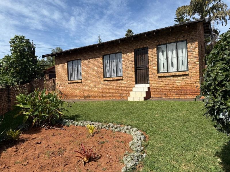 A well-maintained face brick exterior featuring a tiled roof, secure window bars, and a neat garden area with established landscaping.
