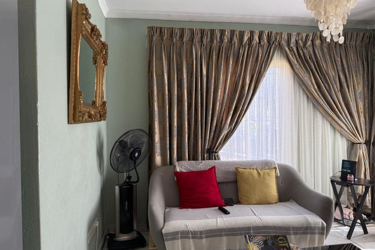 A living room area featuring tiled flooring and window treatments, providing a functional space for relaxation.