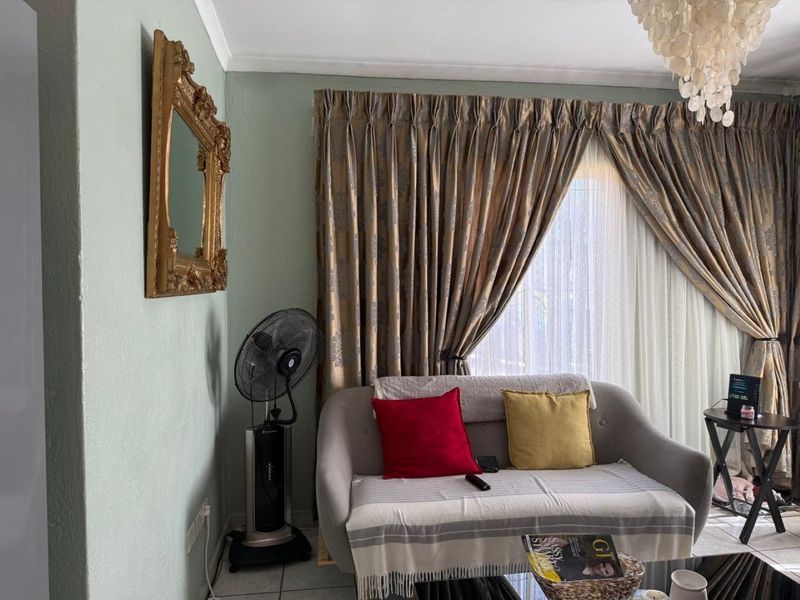 A living room area featuring tiled flooring and window treatments, providing a functional space for relaxation.
