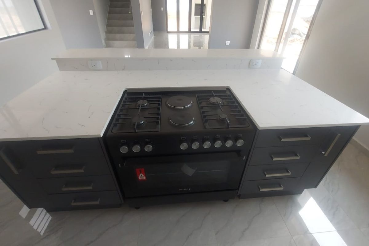 Modern kitchen island featuring a white quartz countertop, integrated gas and electric stove, oven, and dark cabinetry with ample storage space.