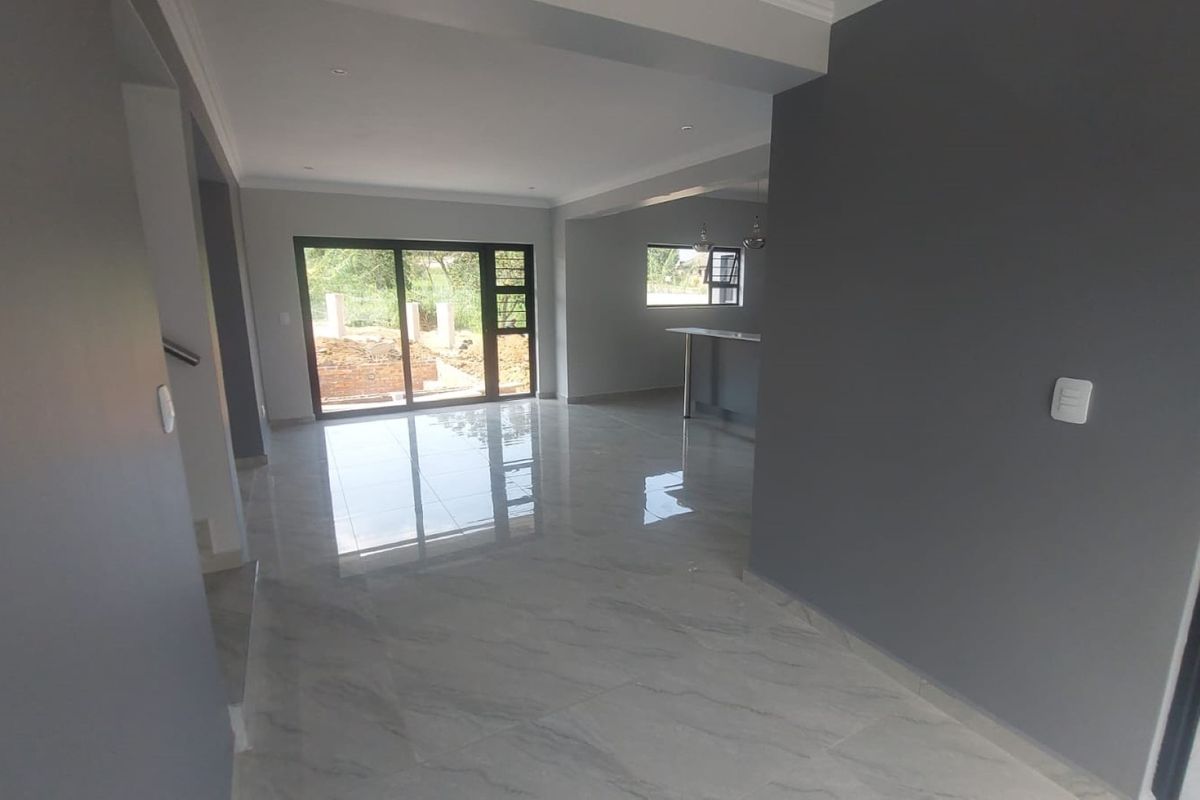 Spacious open-plan living area featuring modern porcelain tile flooring, recessed lighting, and large sliding glass doors leading to the exterior.