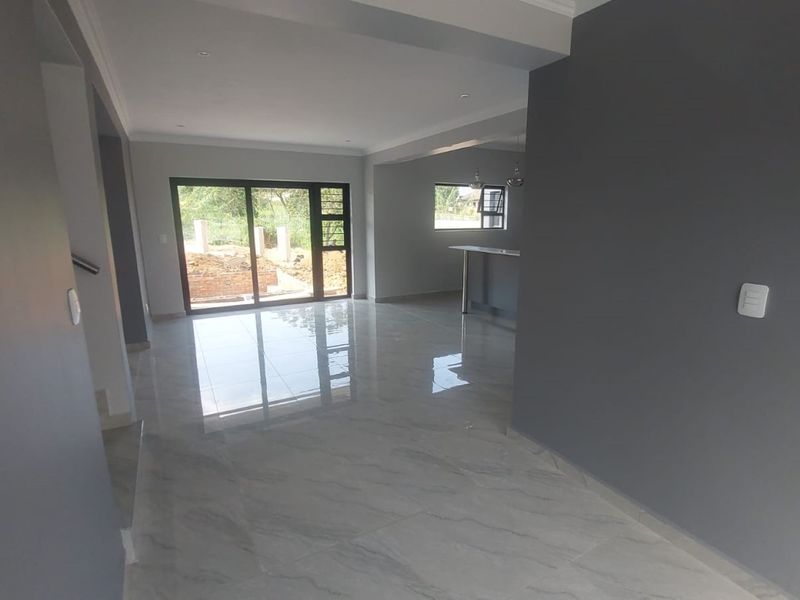 Spacious open-plan living area featuring modern porcelain tile flooring, recessed lighting, and large sliding glass doors leading to the exterior.