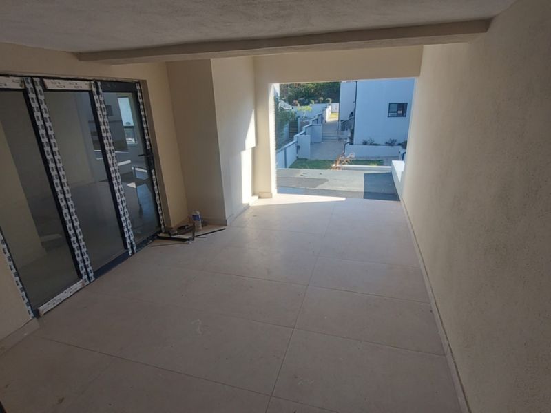 A covered patio area featuring large format floor tiles and modern sliding glass doors, providing a seamless transition to the outdoor space.
