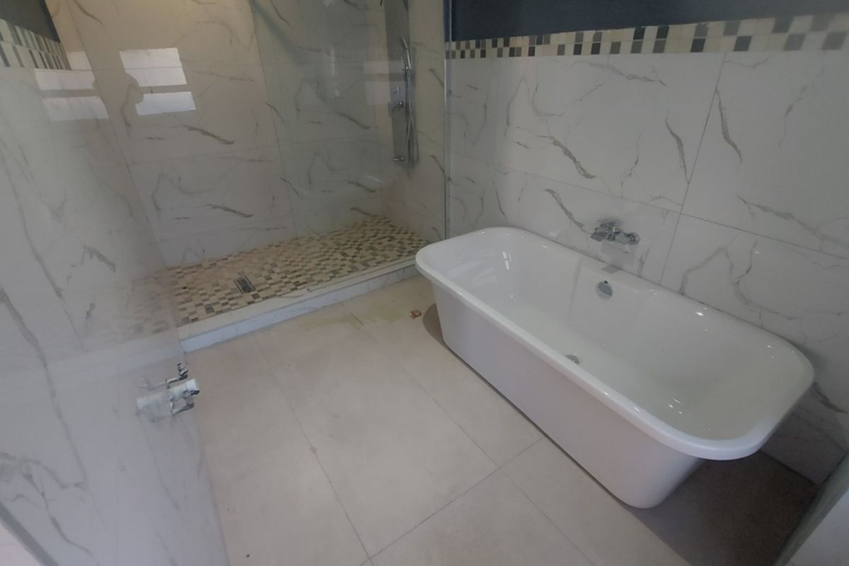 Modern bathroom featuring a freestanding bathtub, a spacious walk-in shower with glass enclosure, and elegant marble-look wall tiling.