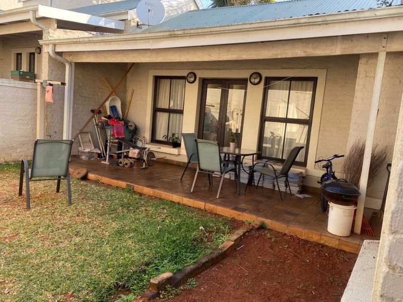 A covered patio area featuring tiled flooring and direct access to the interior through french doors, overlooking a small garden space.