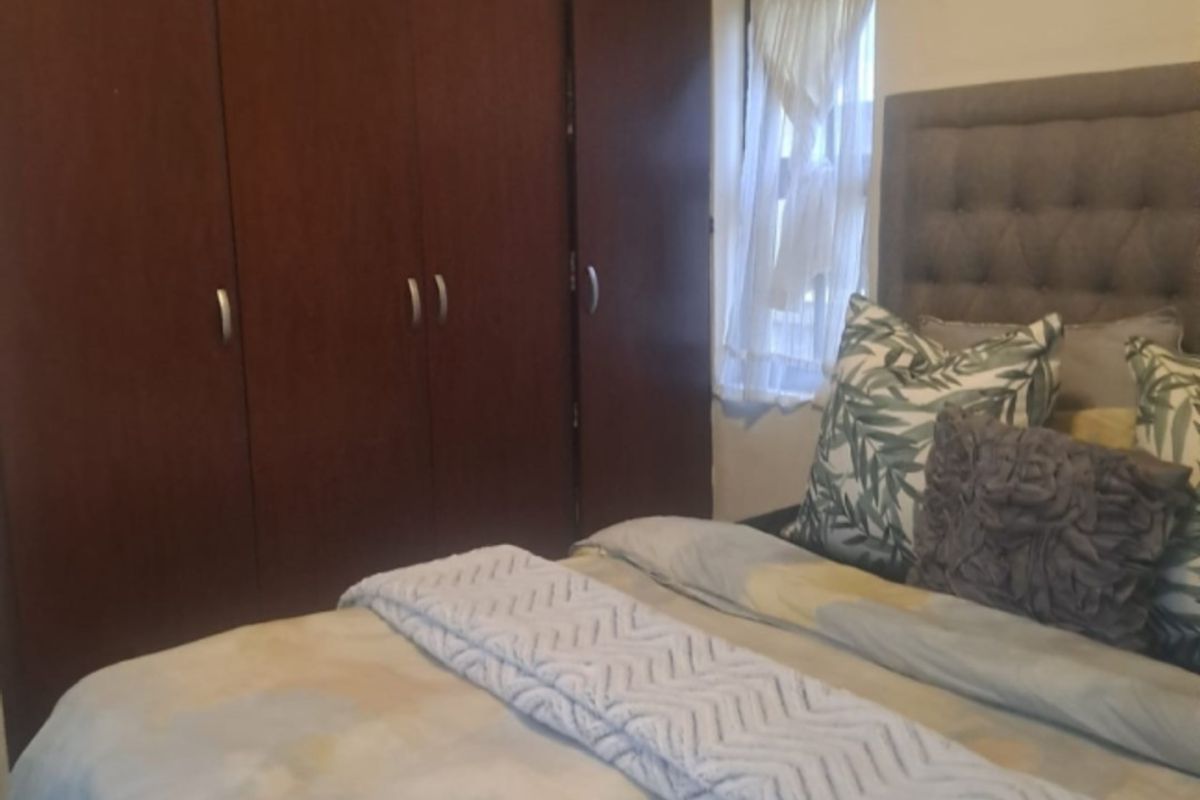 A bedroom featuring dark wood built-in wardrobes and a window with natural light.