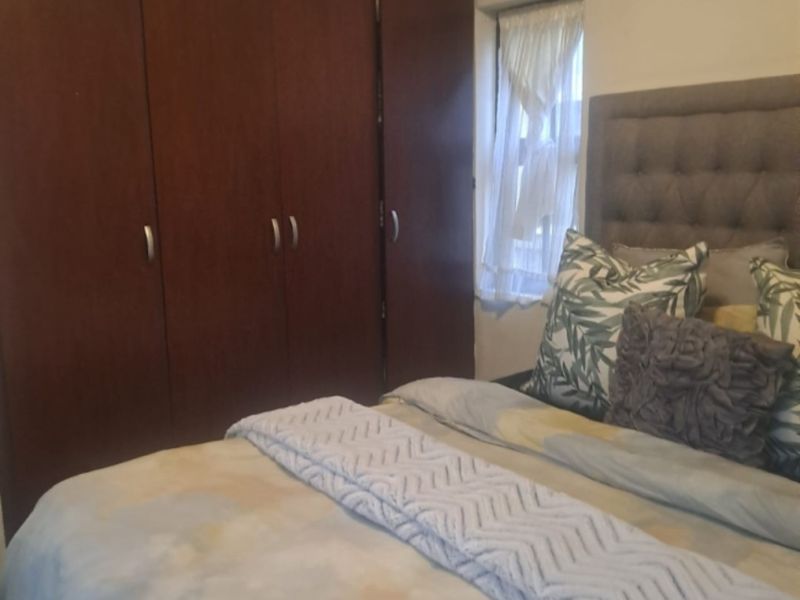 A bedroom featuring dark wood built-in wardrobes and a window with natural light.