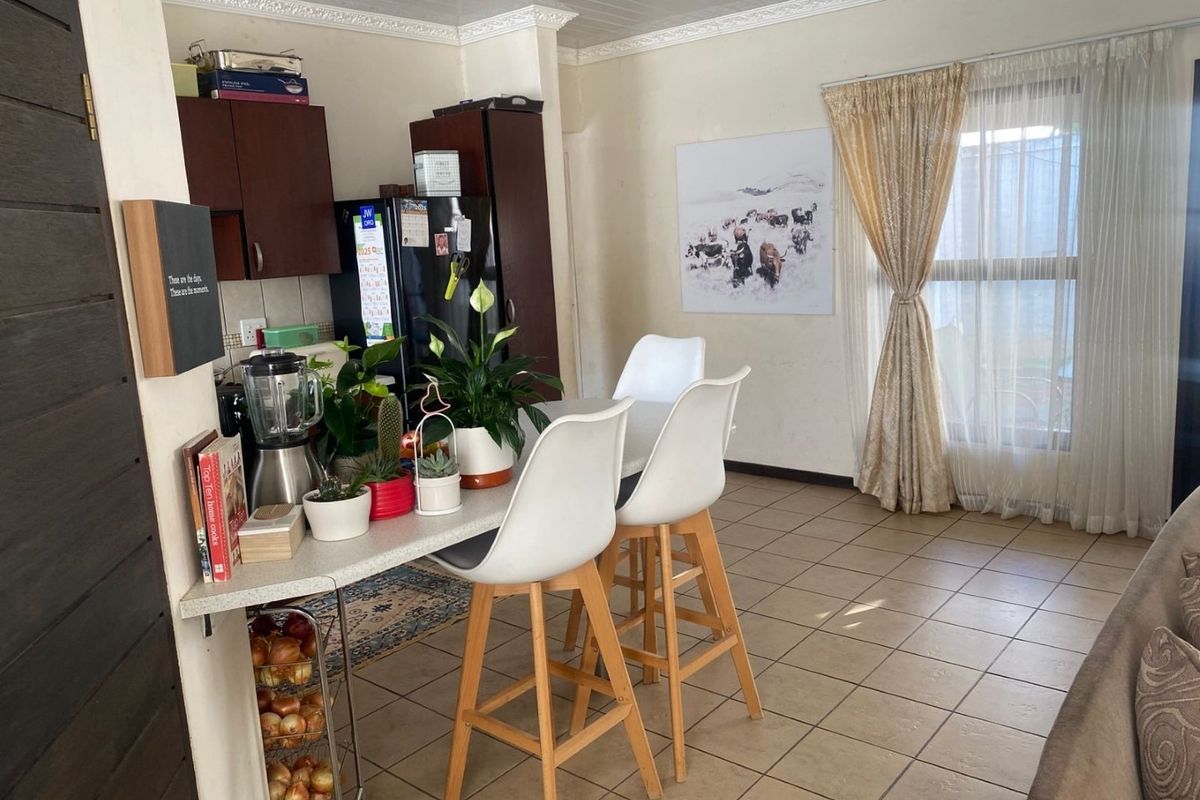A functional kitchen area featuring tiled flooring, built-in cabinetry, and a breakfast bar, with a window providing natural light.
