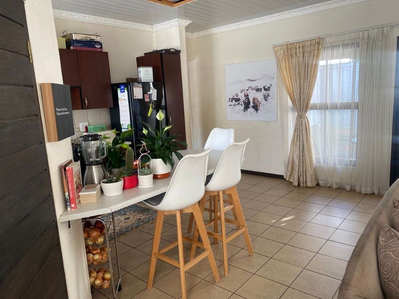 A functional kitchen area featuring tiled flooring, built-in cabinetry, and a breakfast bar, with a window providing natural light.