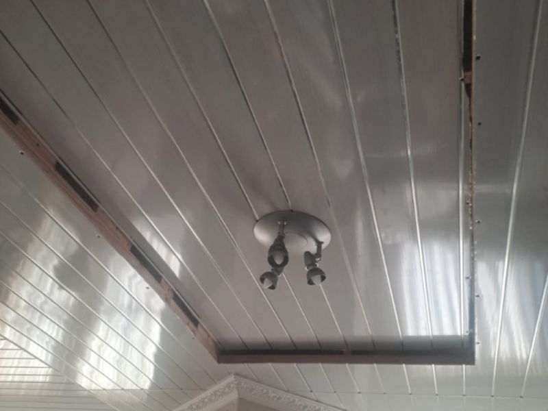 A view of an unfinished ceiling featuring PVC paneling with exposed timber framing and a mounted spotlight fixture.