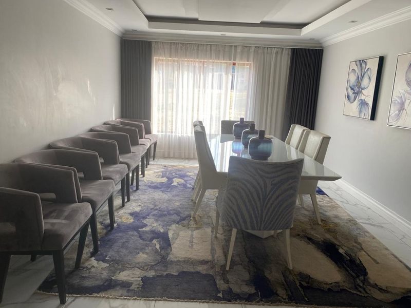 A formal dining room featuring a recessed ceiling with cove lighting and polished marble-look floor tiles.