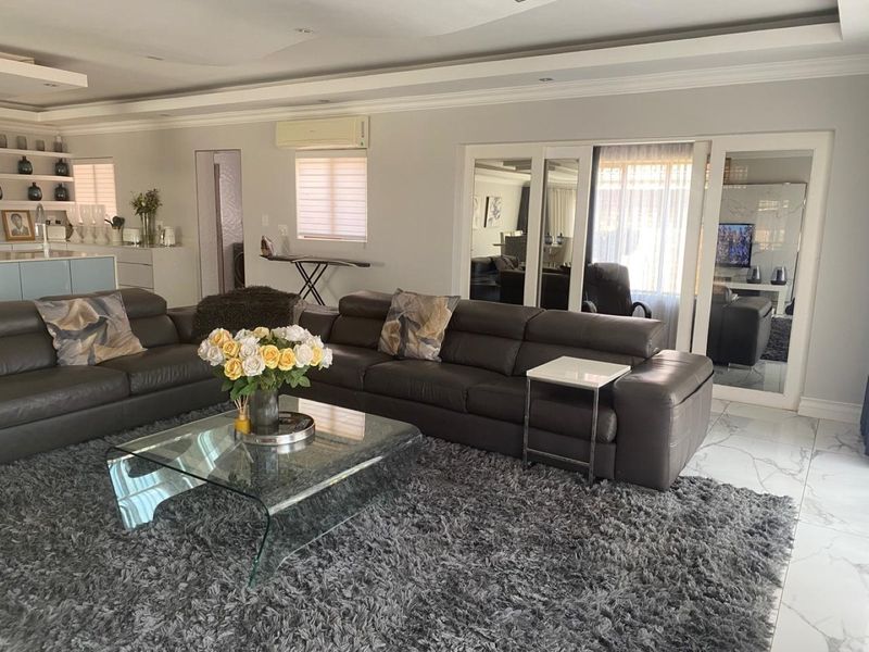 Spacious open-plan living area featuring modern marble-look flooring, recessed ceiling details, and seamless flow into the adjacent kitchen and secondary living space.