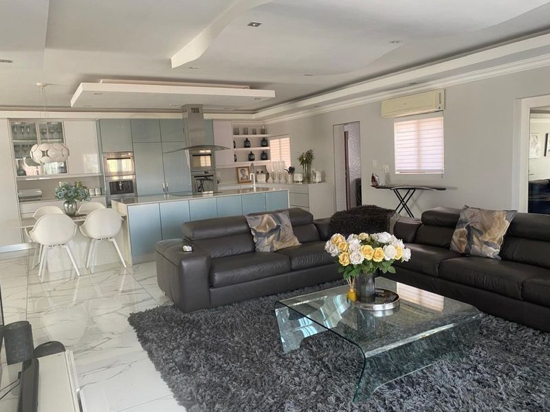Spacious open-plan living area featuring a modern kitchen with a central island, sleek cabinetry, and high-gloss marble-look flooring throughout.
