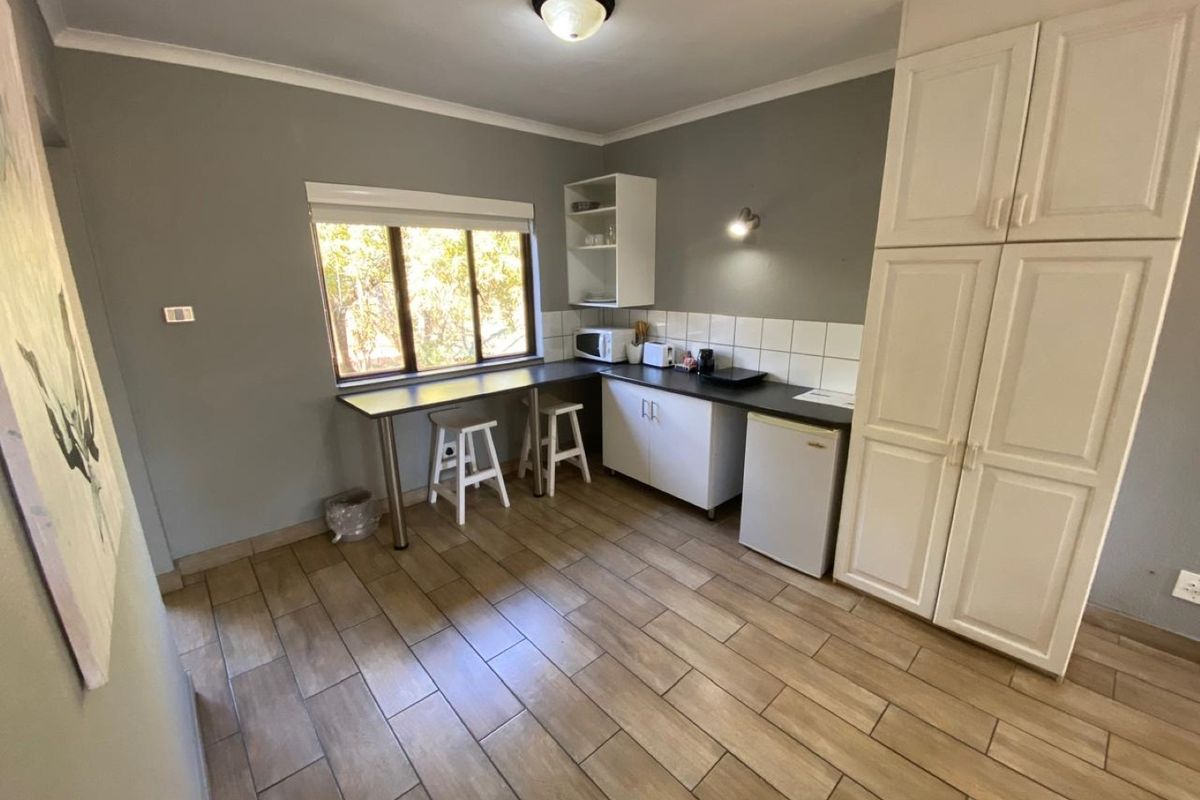 A functional kitchen area featuring tiled flooring, built-in cabinetry, a tiled backsplash, and a convenient integrated breakfast bar.