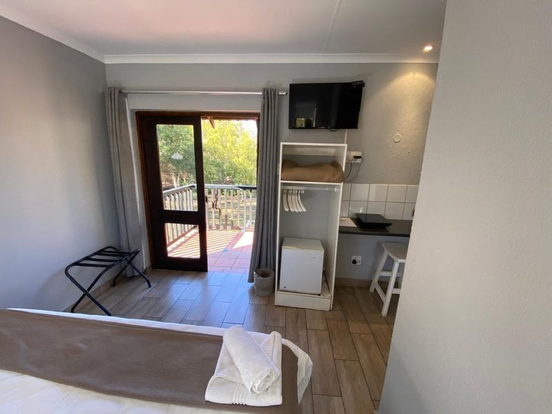 A bedroom featuring tiled flooring, built-in storage, and a glass sliding door providing access to an outdoor balcony area.