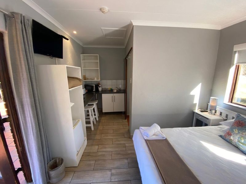 A bedroom featuring tiled flooring, cove cornicing, and a compact built-in kitchenette area with sink and cabinetry.