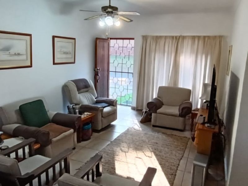 A living room featuring tiled flooring, a ceiling fan, and a security gate leading to the exterior.