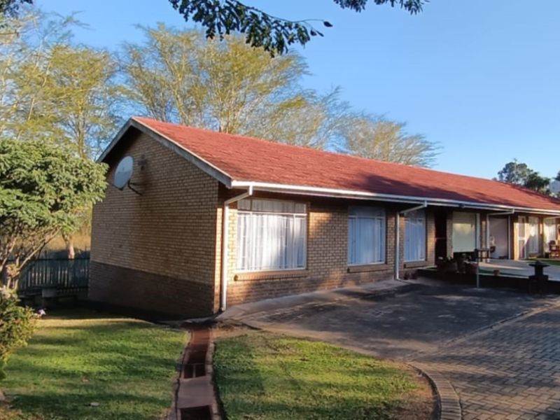 Front exterior view of a face-brick duet property featuring a pitched tiled roof, paved driveway, and established garden surroundings.