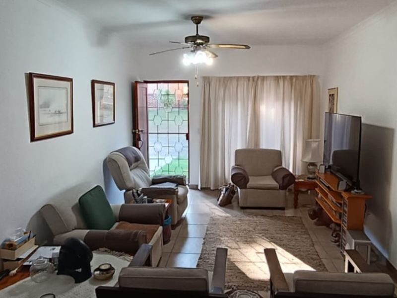 A comfortable living room featuring tiled flooring, a ceiling fan, and direct access to the exterior through a security gate and sliding door.