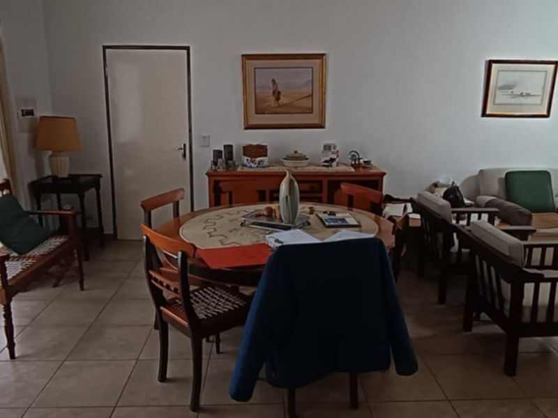 A spacious living and dining area featuring neutral tiled flooring, a ceiling fan, and large sliding glass doors providing natural light.
