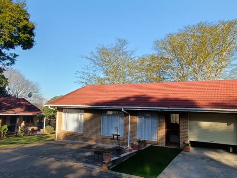 Front view of a duet property featuring a brick facade, tiled roof, and an integrated garage with a paved driveway.