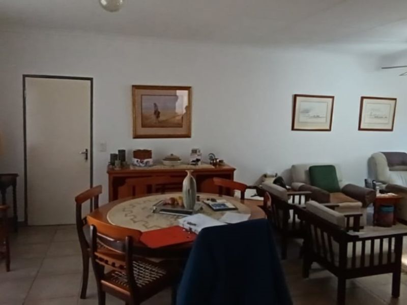 A spacious living area featuring tiled flooring, a ceiling fan, and direct access to the exterior through a security gate.