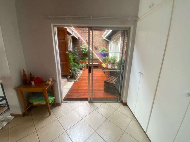 Interior view looking out onto a private wooden deck patio area, featuring tiled flooring and built-in storage cupboards.