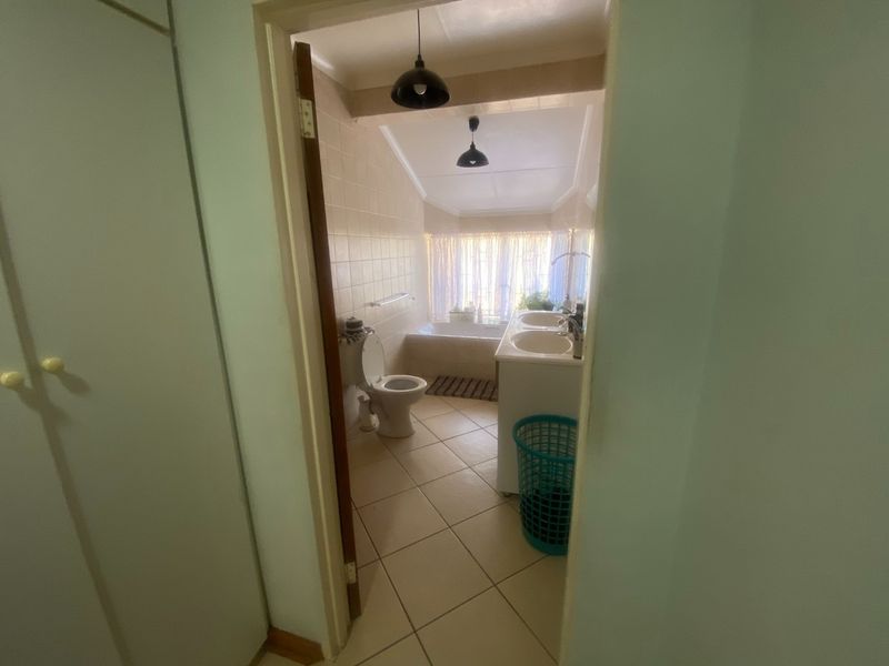 A functional bathroom featuring a dual vanity, bathtub, and toilet with tiled finishes and pendant lighting.
