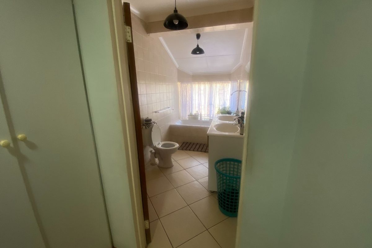 A functional bathroom featuring a dual vanity, bathtub, and toilet with tiled finishes and pendant lighting.