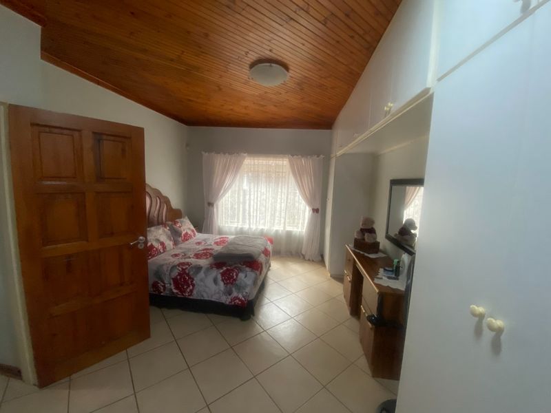 A bedroom featuring tiled flooring, a timber-clad ceiling, and built-in storage cupboards.