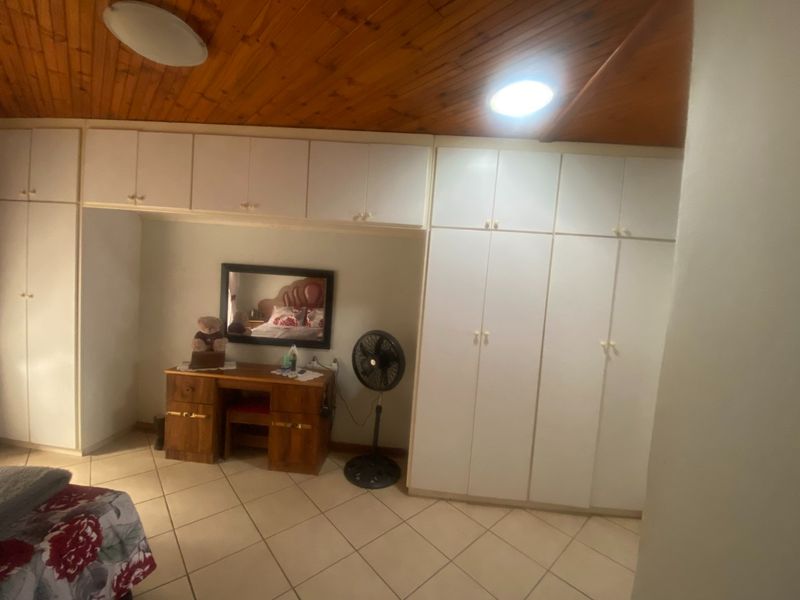 Bedroom featuring extensive built-in white cabinetry, warm wooden ceiling paneling, and neutral tiled flooring.