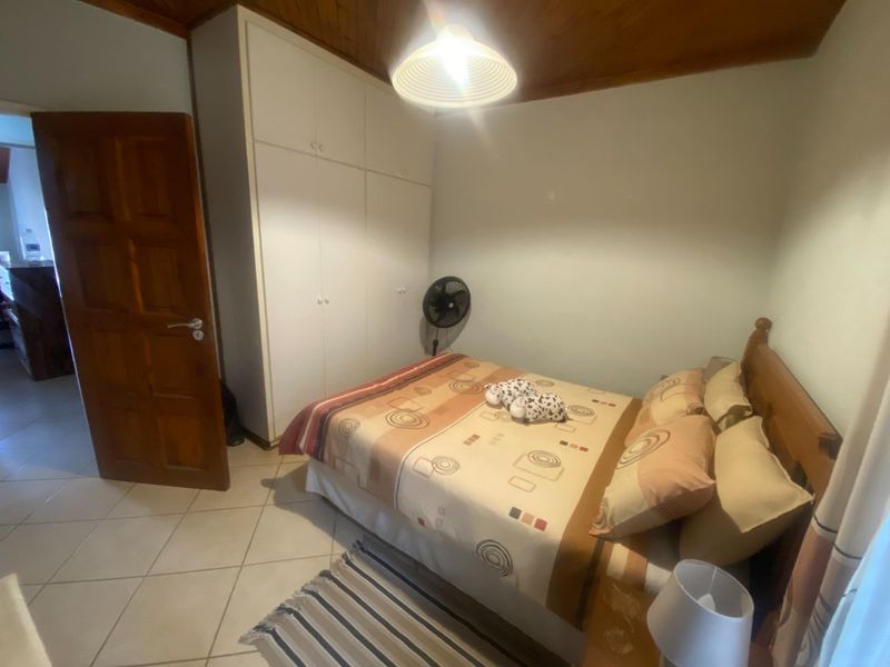 A bedroom featuring built-in cupboards, tiled flooring, and a timber-paneled ceiling.