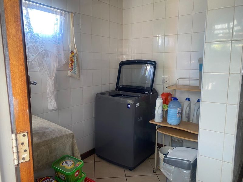 A functional laundry room featuring tiled walls and flooring, providing a practical space for washing and utility tasks.