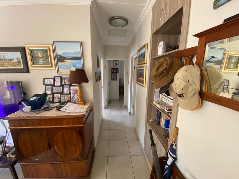 A functional hallway featuring tiled flooring, a built-in shelving unit, and neutral wall finishes, providing access to other areas of the home.