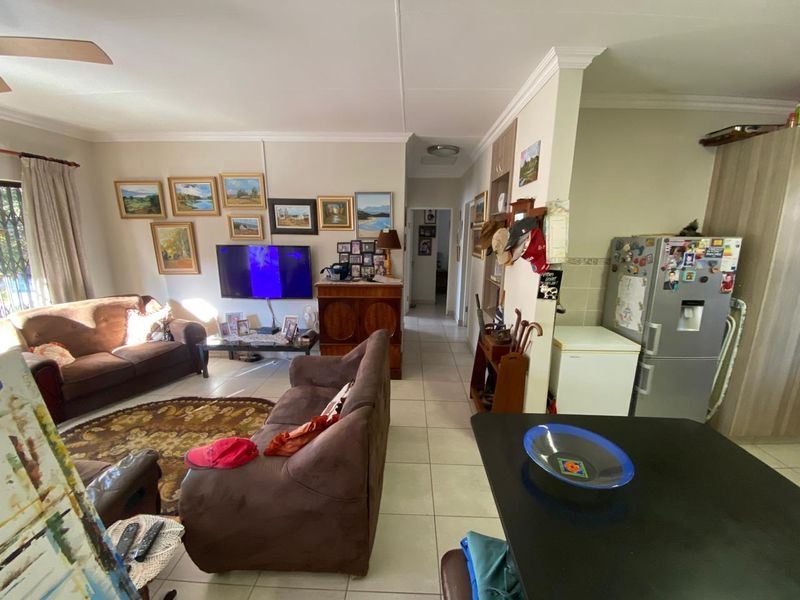Open-plan living area featuring tiled flooring, crown molding, and a ceiling fan, providing a functional and connected space for relaxation and dining.
