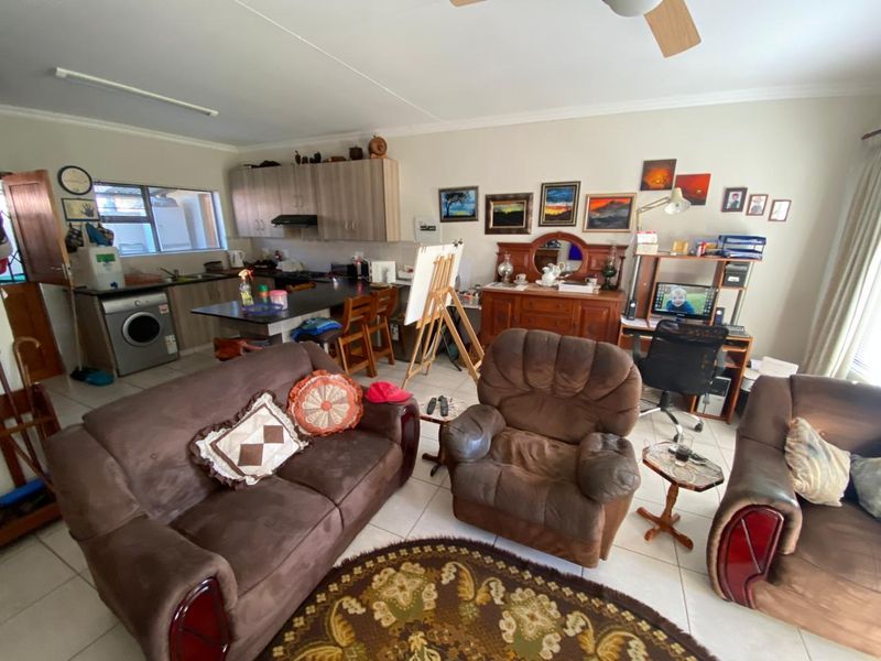 Open-plan living area featuring a functional kitchen with built-in cabinetry, tiled flooring, and a ceiling fan, creating a versatile space for daily living.
